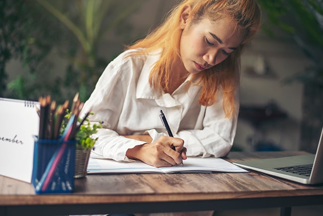 Prüfen Sie Ihre Vielfaltskompetenz! Frau schreibt in ein Arbeitsheft