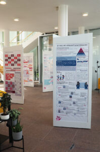 Infosäulen der Wanderausstellung Pfad der Vielfalt mit bunten Grafiken, Stiege im Hintergrund